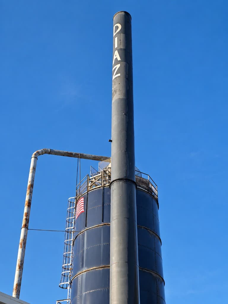 Diaz facility silo with American flag and DIAZ smokestack against a blue sky